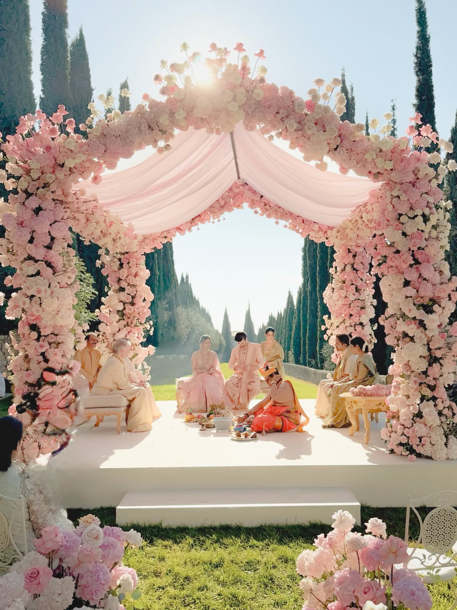 Il mandap di rose rosa e bianche nel giardino, fra i cipressi, il giorno della cerimonia