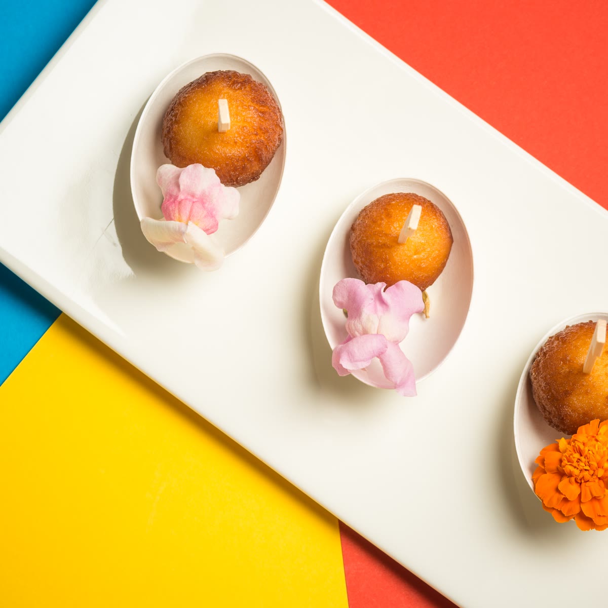 Tre gulab jamun in cucchiai bianchi con petali di rosa