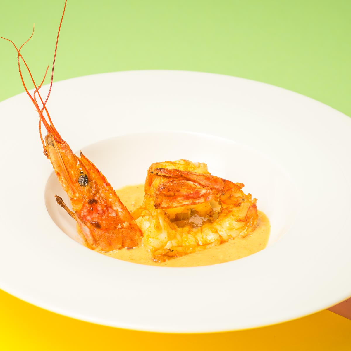 Un gambero reale in salsa al curry su un piatto bianco