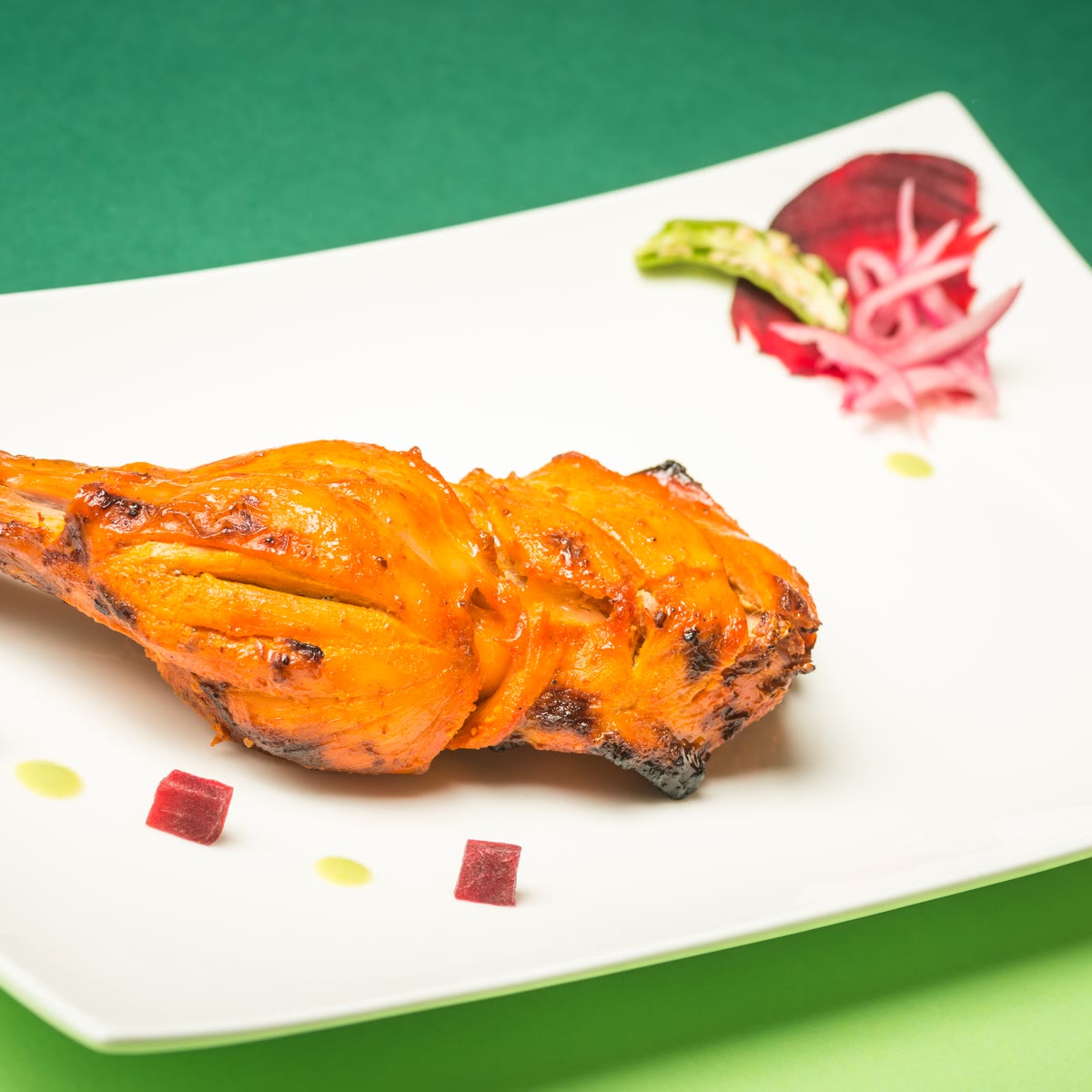 Una coscia di pollo tandoori con barbabietola e cipolla in agrodolce