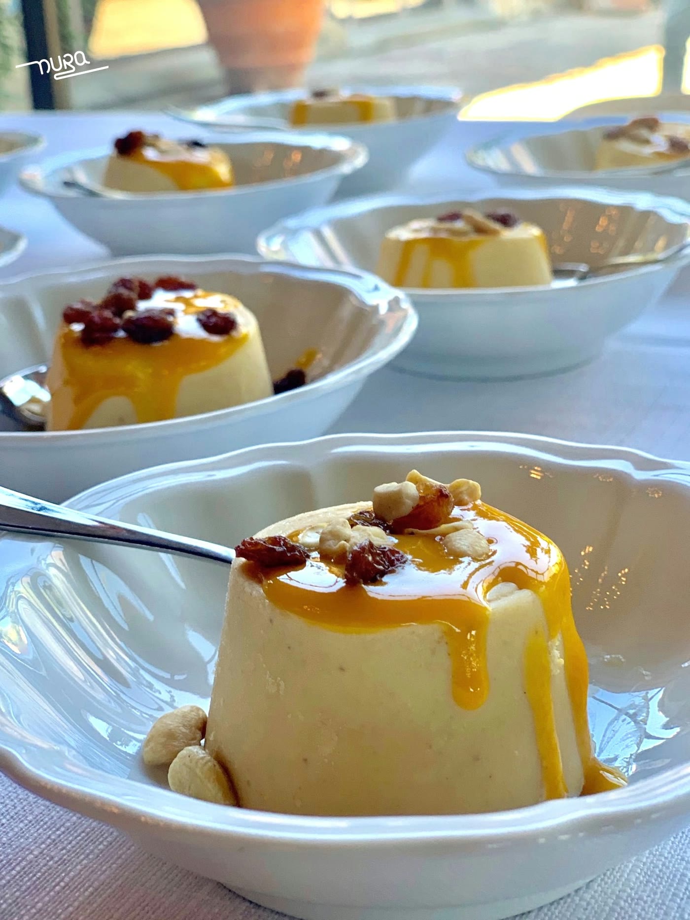 Piccoli dolci in ciotole bianche con sciroppo allo zafferano e pistacchio
