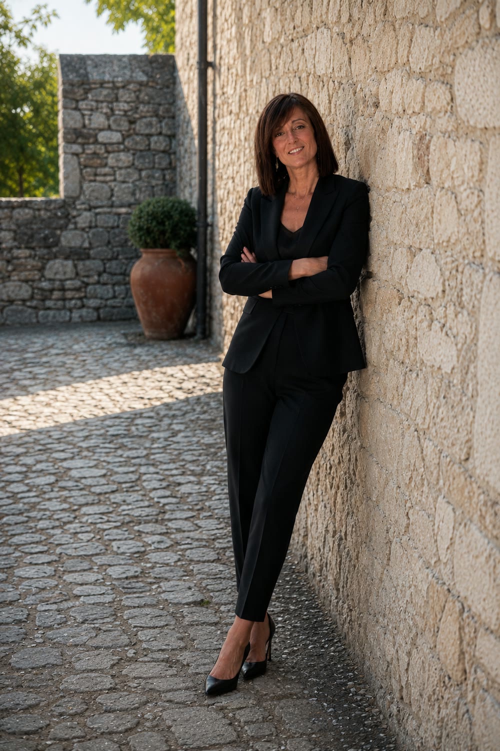 Marta Casati in black, leaning against a stone wall
