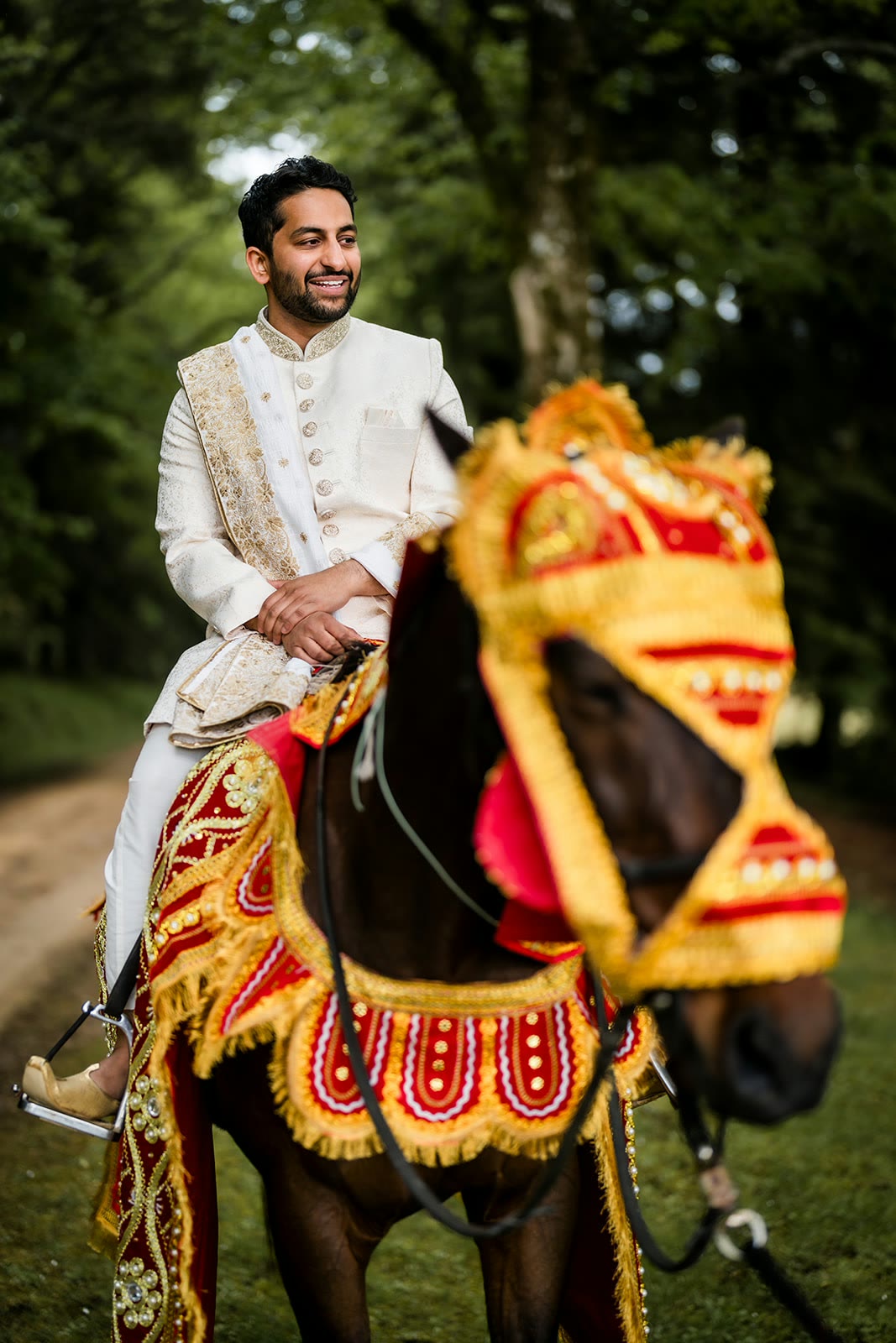 Akshay arriva a cavallo, il cavallo bardato di rosso e oro